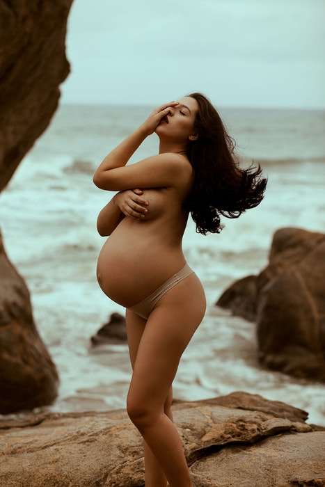 Linda foto de maternidade de uma grávida posando nua na praia
