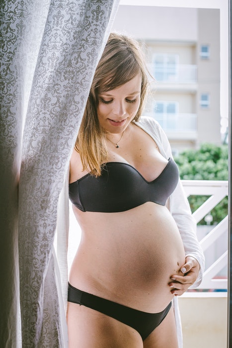 Linda foto de maternidade de uma grávida posando de lingerie