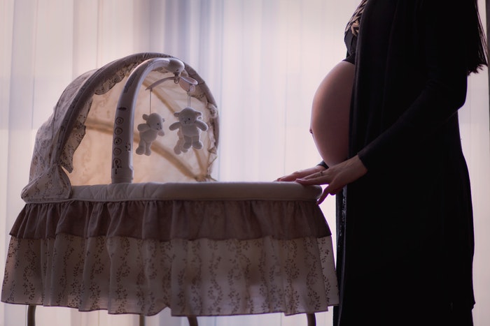 Linda foto de maternidade de uma grávida balançando um berço