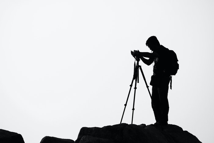 A silhueta de um fotógrafo montando sua câmera em um tripé
