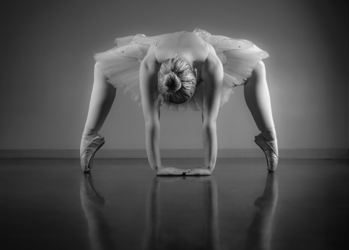 Bailarina graciosa se aquecendo em preto e branco no estúdio de balé