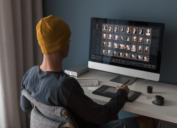Homem trabalhando em casa editando imagens com predefinições do Lightroom no computador