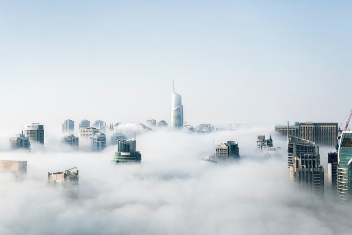 uma fotografia dos arranha-céus da cidade rompendo as nuvens