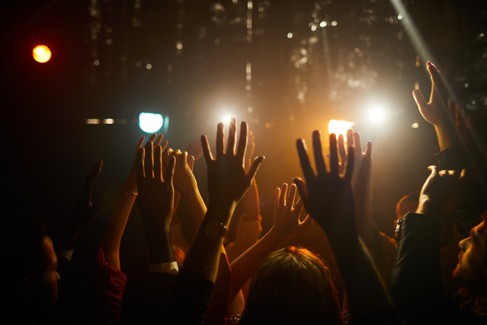 Multidão de pessoas em pé no clube escuro e agitando as mãos no ar