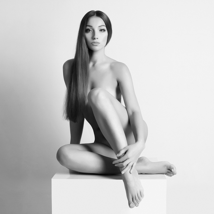 Retrato boudoir de una chica desnuda posando sobre un pedestal 