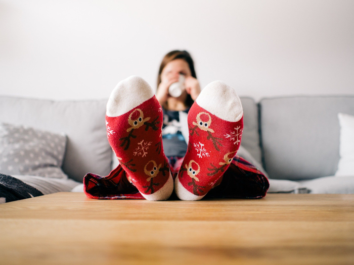 Ideias pessoais para fotos de cartões de Natal de uma mulher em um sofá com meias de Natal 