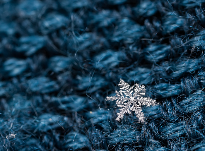 Um pequeno floco de neve pousado sobre lã azul