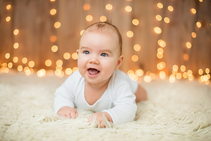 Doce foto de Natal de um bebê em frente às luzes de Natal