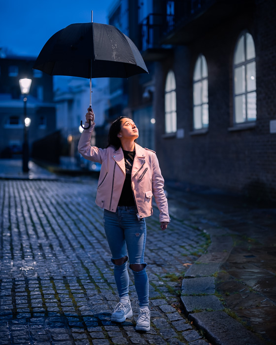 Imagem de retrato de uma menina com um guarda-chuva tirada com a lente Canon RF 50mm f / 1.2L USM à noite