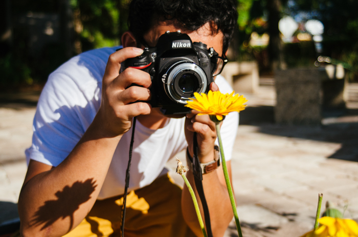 A man taking a photo of a flower
