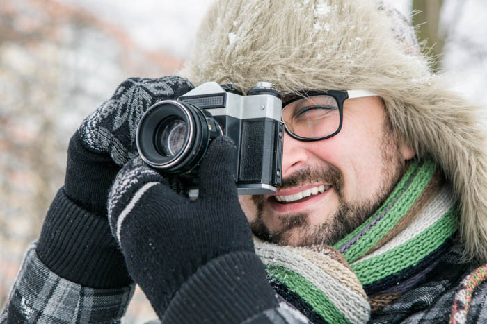 Pria mengambil foto di musim dingin sambil mengenakan sarung tangan fotografi luar ruangan