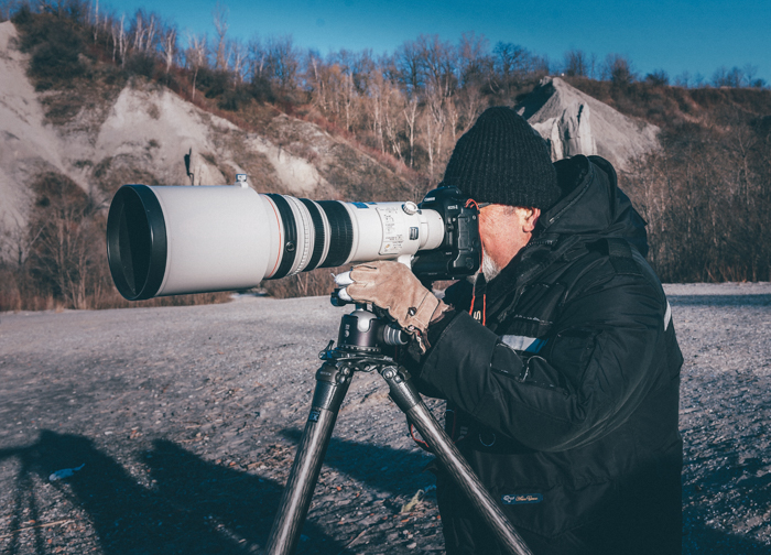 Um fotógrafo da vida selvagem fotografando com um zoom supertelefoto