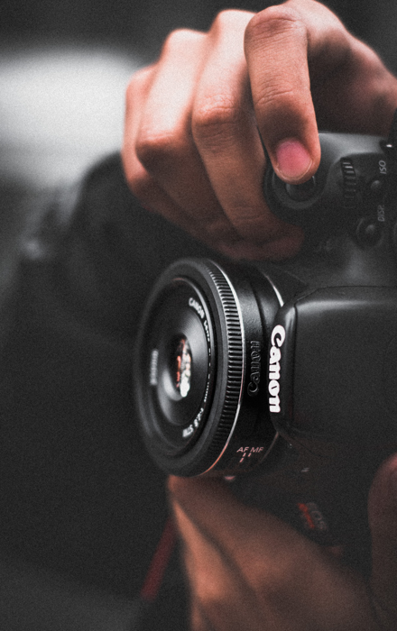 uma imagem em close de um homem tirando uma foto lateral com uma Canon DSLR