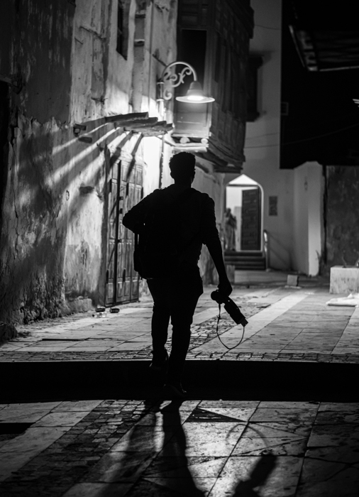 silhueta em preto e branco de um fotógrafo perto de um poste de luz 