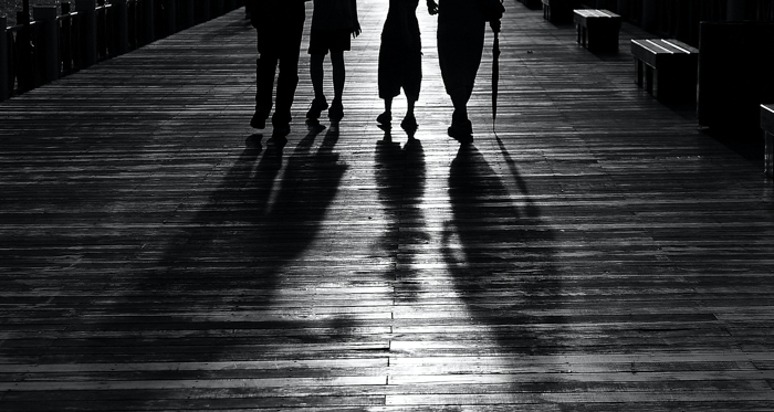 imagem em preto e branco de quatro pessoas da cintura para baixo com sombras 