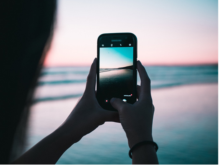 pessoa tirando foto de smartphone na praia